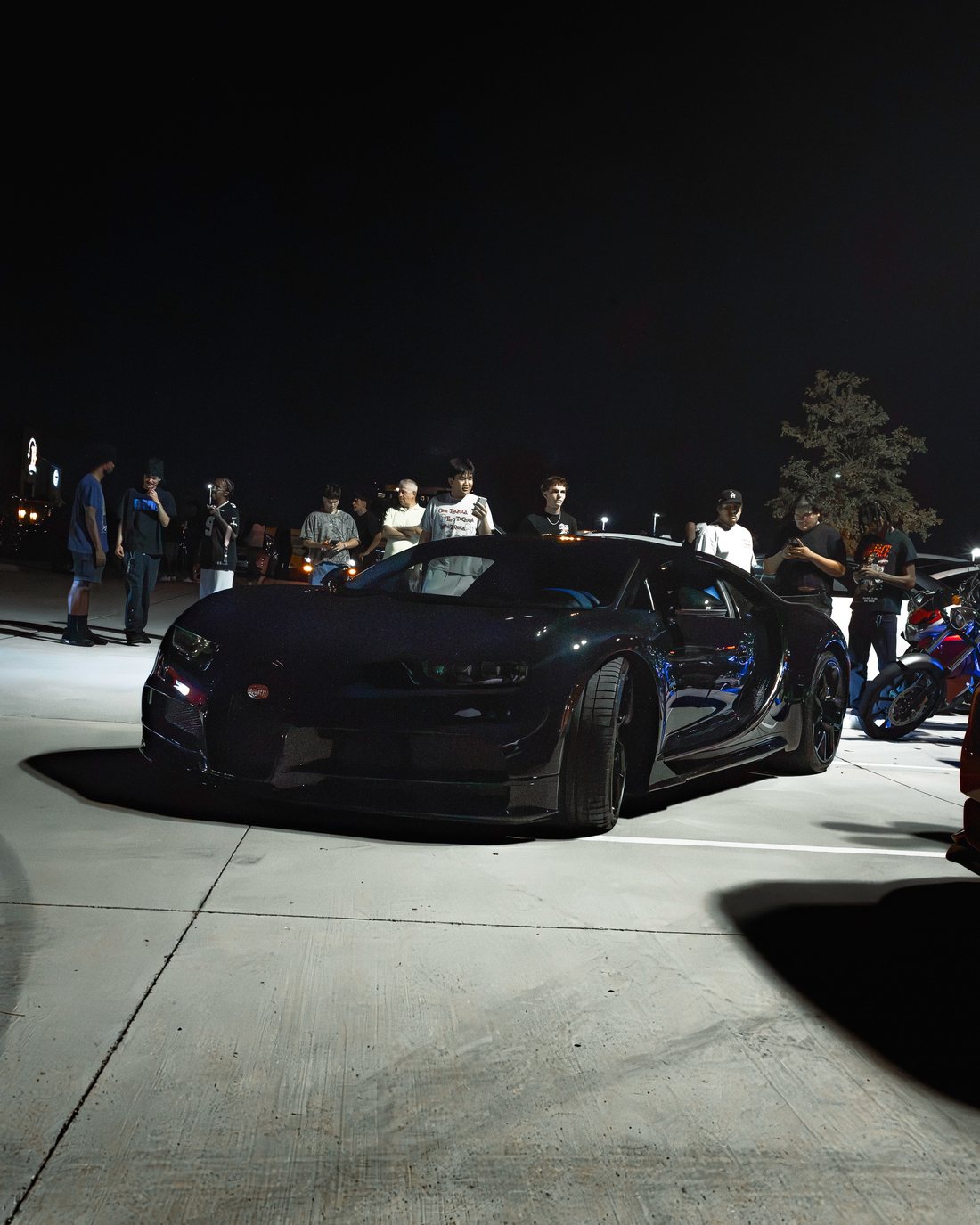 Crowd gathered around a Bugatti Chiron under the night sky