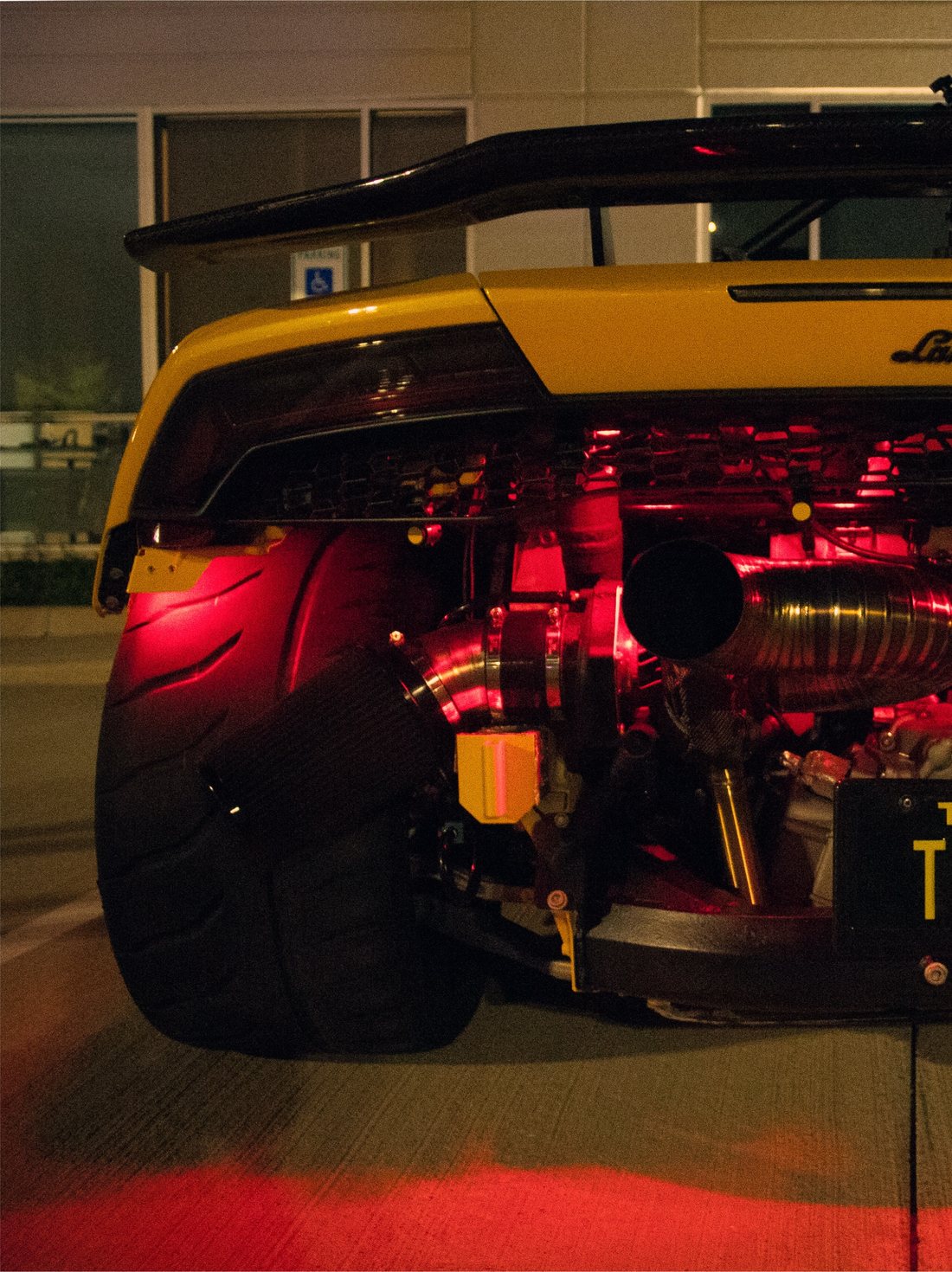 Rear of a modified supercar glowing red with the crowd behind it